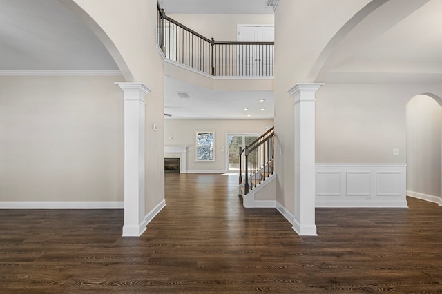 entrance foyer with decorative columns, ornamental molding, and dark wood-type flooring