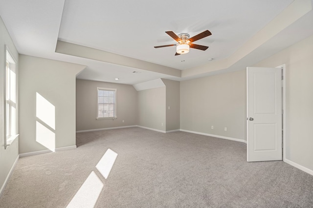 spare room featuring light carpet, ceiling fan, and a tray ceiling