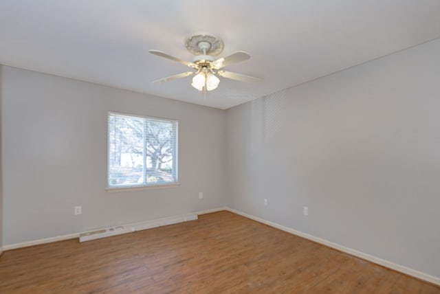 empty room with ceiling fan, wood finished floors, and baseboards