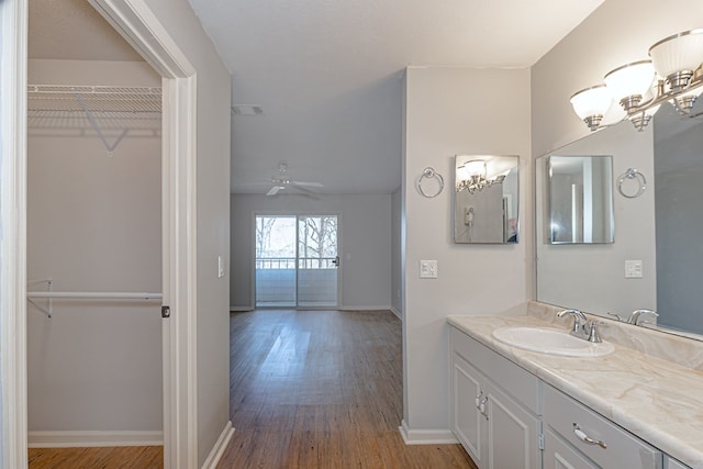 bathroom featuring ceiling fan with notable chandelier, wood finished floors, visible vents, vanity, and a spacious closet