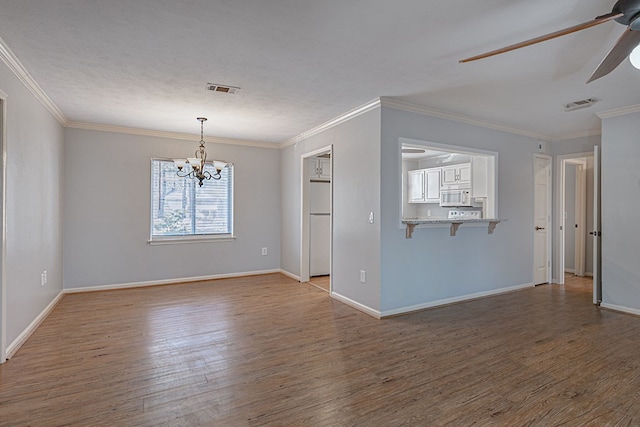 unfurnished room with ceiling fan with notable chandelier, ornamental molding, wood finished floors, and visible vents