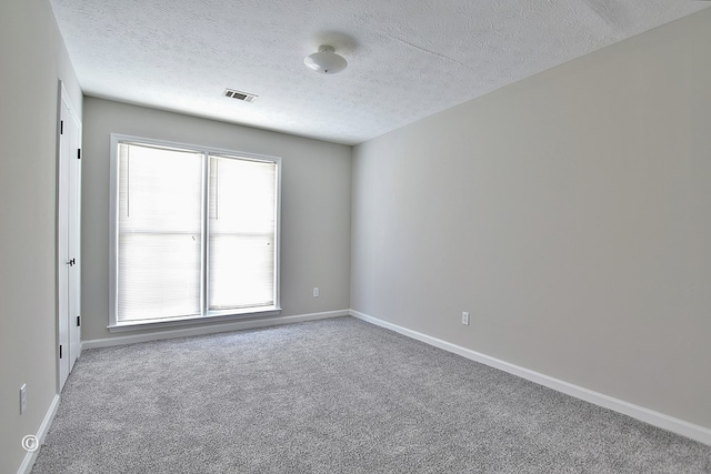 unfurnished room with baseboards, visible vents, carpet floors, and a textured ceiling