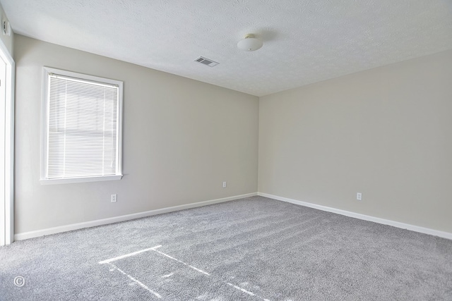 carpeted spare room with visible vents, baseboards, and a textured ceiling