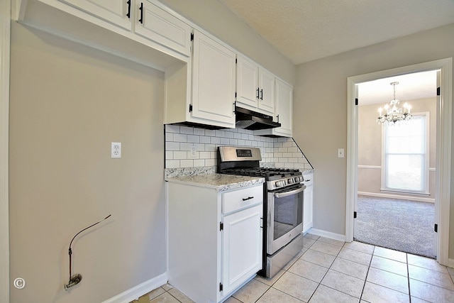 kitchen featuring light tile patterned floors, under cabinet range hood, white cabinetry, gas range, and tasteful backsplash