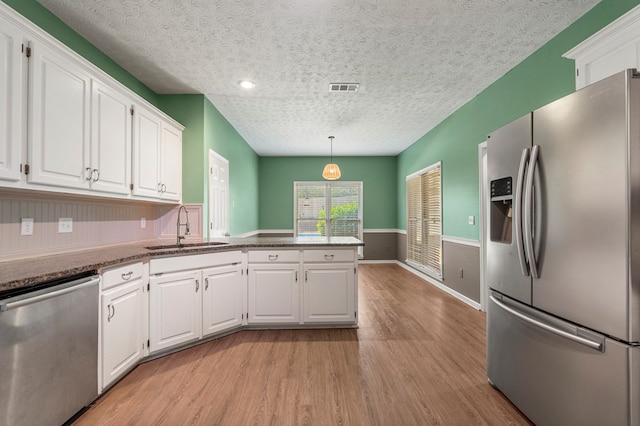 7310 Westport Loop, Midland, GA 31820 - kitchen with stainless steel appliances, a sink, a peninsula, a textured ceiling, and white cabinets