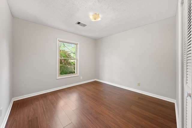empty room with baseboards, dark wood-style flooring, and a textured ceiling