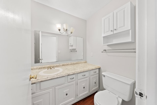 bathroom with vanity, toilet, wood finished floors, and a chandelier