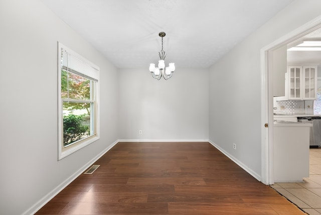 unfurnished dining area featuring a chandelier, baseboards, and wood finished floors