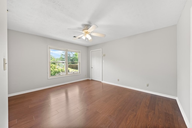 spare room with a ceiling fan, baseboards, dark wood finished floors, and a textured ceiling