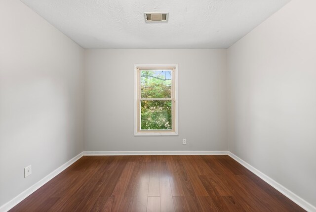 empty room featuring dark wood-type flooring and baseboards