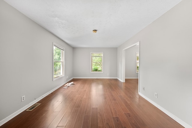spare room with baseboards, wood finished floors, and a textured ceiling
