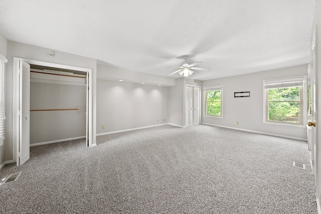unfurnished bedroom featuring multiple closets, carpet, baseboards, and ceiling fan