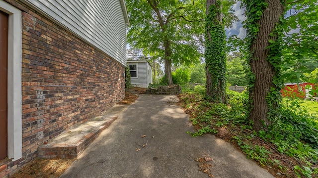 view of side of property featuring brick siding, fence, and a patio