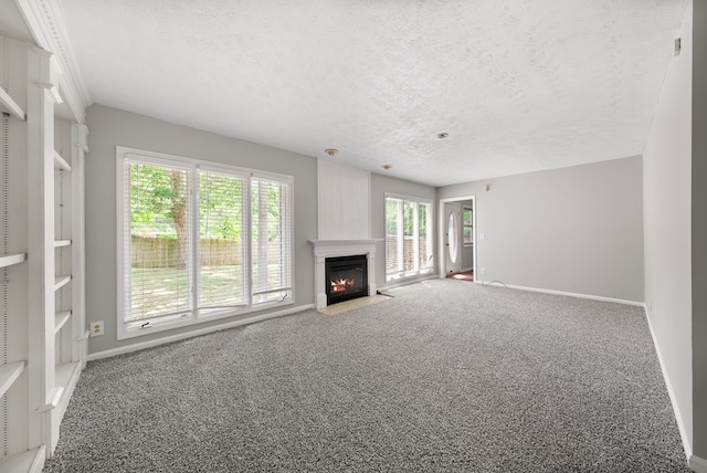 unfurnished living room featuring carpet floors, a fireplace with flush hearth, a textured ceiling, and baseboards