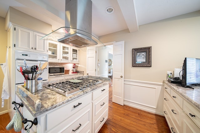 6130 Bristol Blvd, Columbus, GA 31904 - kitchen featuring appliances with stainless steel finishes, island exhaust hood, wood finished floors, glass insert cabinets, and light stone countertops