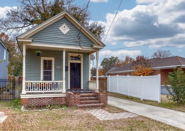 shotgun-style home with a porch and fence