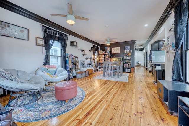 living area with ornamental molding, ceiling fan, and light wood-style flooring