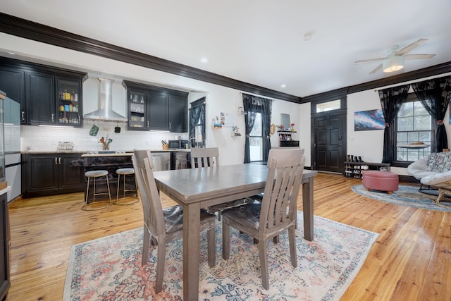 dining space featuring ornamental molding, ceiling fan, and light wood-style flooring