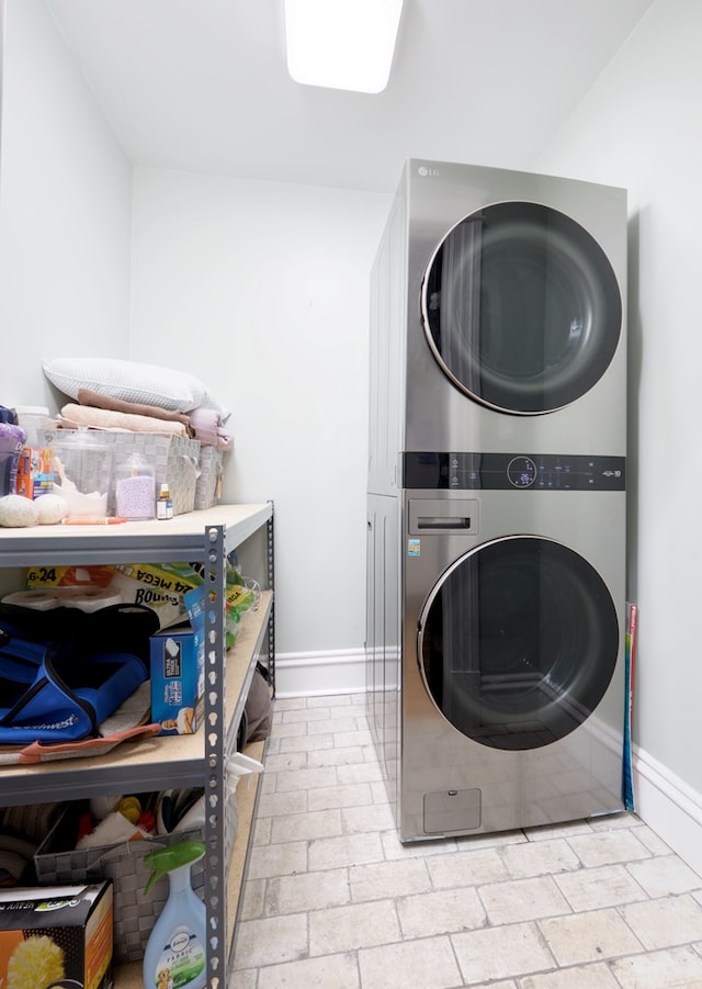 laundry room with stacked washer and dryer, baseboards, laundry area, and brick floor