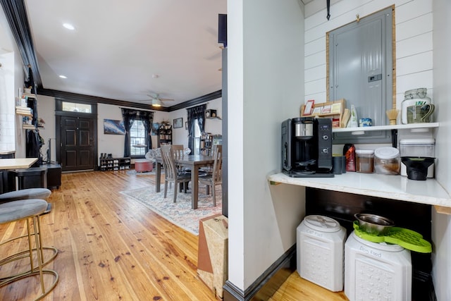 interior space with light wood finished floors, ornamental molding, ceiling fan, electric panel, and baseboards