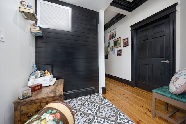 foyer with crown molding, light wood finished floors, wood walls, and baseboards