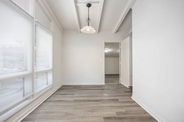 unfurnished dining area featuring hardwood / wood-style flooring and beamed ceiling