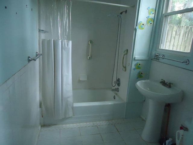 bathroom with tile patterned flooring, shower / bath combination with curtain, and sink