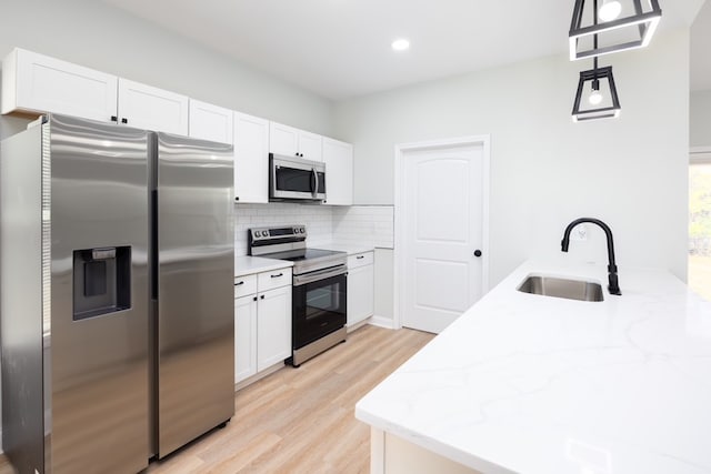 kitchen with a sink, decorative backsplash, appliances with stainless steel finishes, and white cabinets