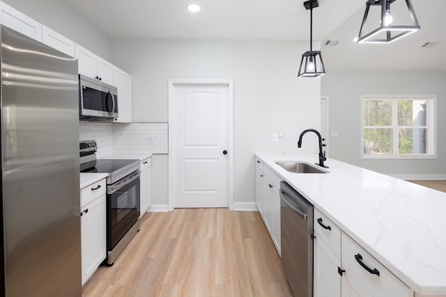 kitchen featuring visible vents, a sink, appliances with stainless steel finishes, a peninsula, and decorative backsplash