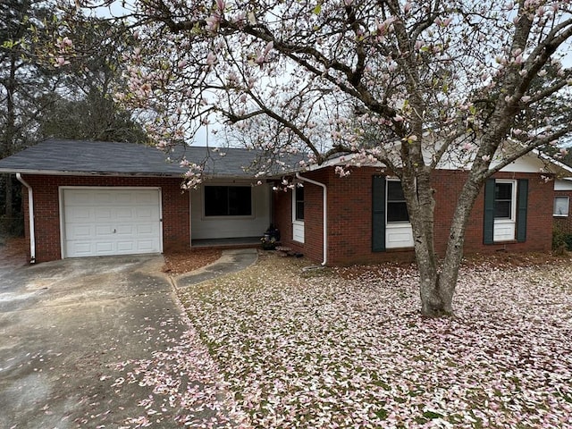 single story home with driveway, brick siding, and an attached garage