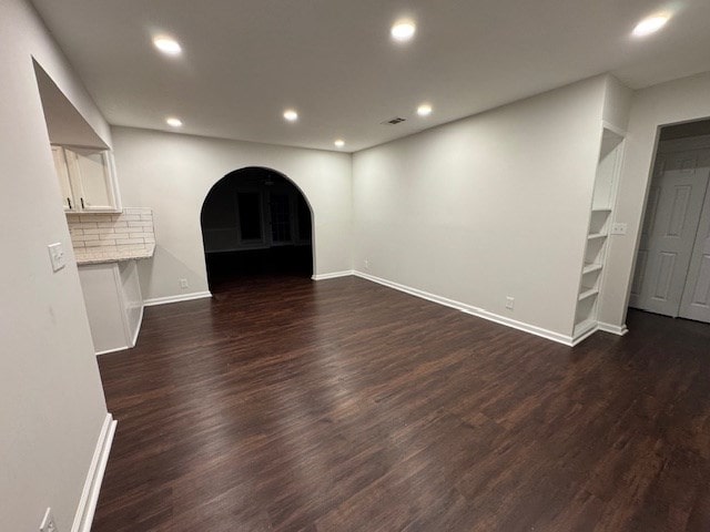 unfurnished living room with recessed lighting, dark wood-style floors, and arched walkways