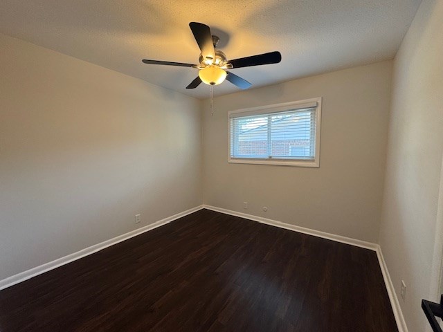 spare room with dark wood finished floors, a textured ceiling, a ceiling fan, and baseboards