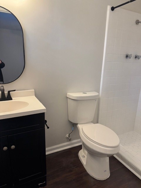 bathroom featuring toilet, a stall shower, wood finished floors, baseboards, and vanity