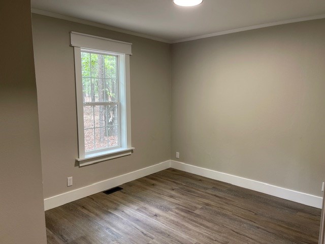 62 Brannon Montgomery Rd, Mauk, GA 31058 - unfurnished room with crown molding, baseboards, dark wood finished floors, and visible vents