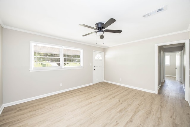 empty room featuring crown molding, light wood finished floors, baseboards, and a ceiling fan