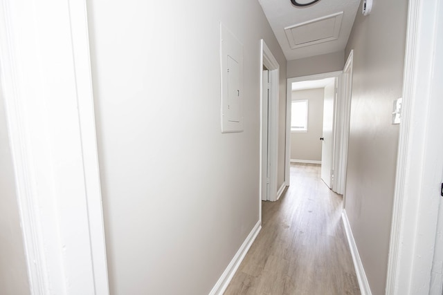 hall with light wood-style flooring and baseboards