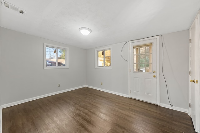 empty room featuring a textured ceiling, dark hardwood / wood-style flooring, vaulted ceiling, and plenty of natural light