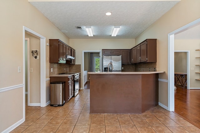 7096 Southwind Ct, Columbus, GA 31909 - kitchen featuring stainless steel appliances, dark brown cabinetry, under cabinet range hood, backsplash, and a textured ceiling