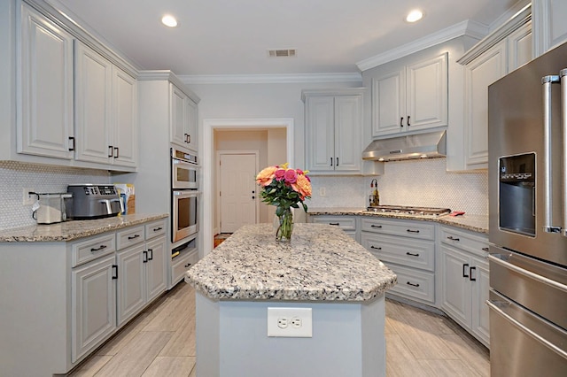 5023 Masters Ln, Columbus, GA 31909 - kitchen featuring appliances with stainless steel finishes, under cabinet range hood, a center island, backsplash, and crown molding