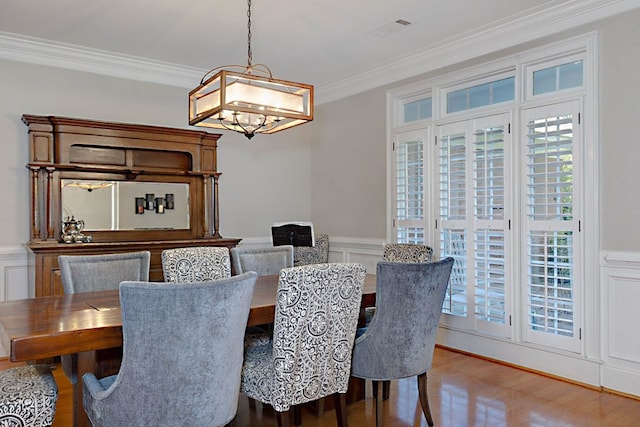5023 Masters Ln, Columbus, GA 31909 - dining space with ornamental molding, a chandelier, a decorative wall, a wainscoted wall, and wood finished floors