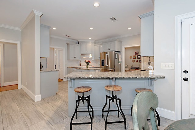 5023 Masters Ln, Columbus, GA 31909 - kitchen with high end refrigerator, under cabinet range hood, a peninsula, light stone countertops, and a breakfast bar