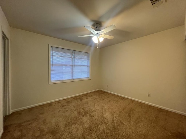 carpeted spare room with a ceiling fan, visible vents, and baseboards