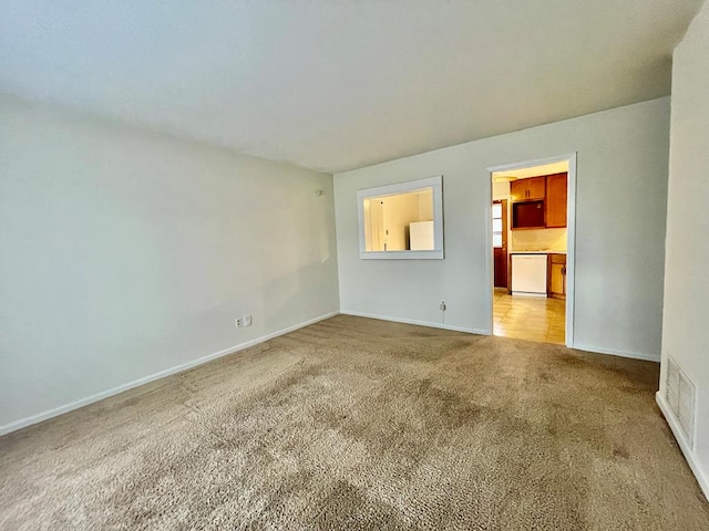 spare room featuring baseboards and light carpet