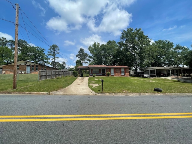 ranch-style home with a front lawn, concrete driveway, fence, and an attached carport