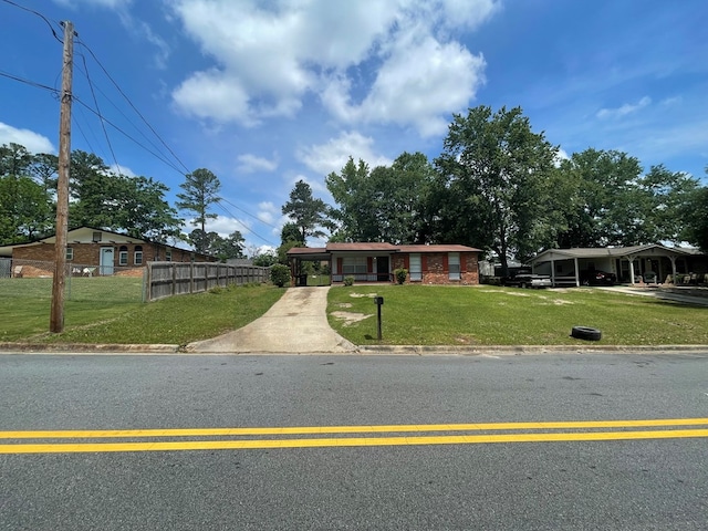 ranch-style house with a front lawn, driveway, fence, and an attached carport