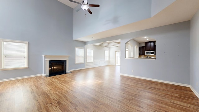 7315 San Vista Dr, Columbus, GA 31909 - unfurnished living room featuring a ceiling fan, high vaulted ceiling, light wood-type flooring, a fireplace with flush hearth, and arched walkways
