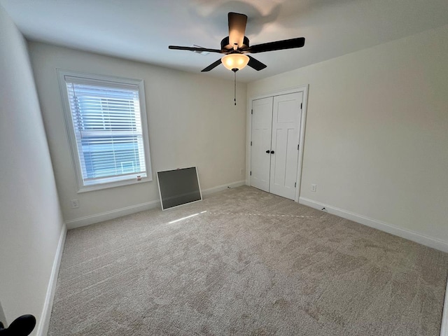 unfurnished bedroom featuring light colored carpet, a closet, and ceiling fan