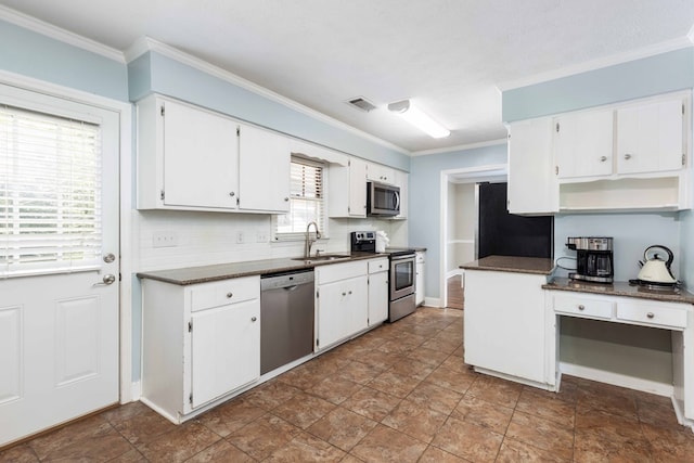 4 David Ct, Columbus, GA 31909 - kitchen featuring appliances with stainless steel finishes, dark countertops, crown molding, white cabinets, and tasteful backsplash