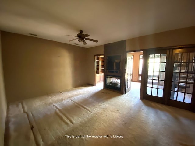 unfurnished living room featuring ceiling fan, french doors, and light carpet