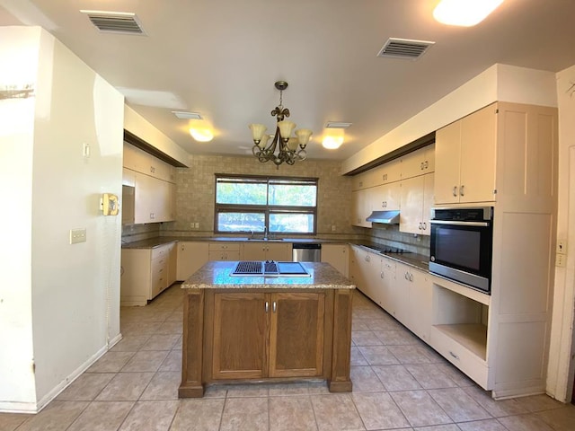 kitchen with a center island, a chandelier, decorative light fixtures, light tile patterned flooring, and appliances with stainless steel finishes